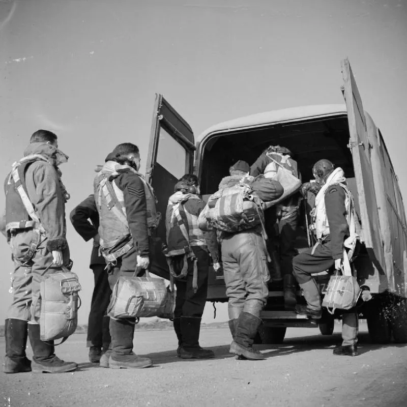 A Lancaster crew of No 57 Squadron, laden with parachutes and flying kit, board a van at RAF Scampton, February 1943