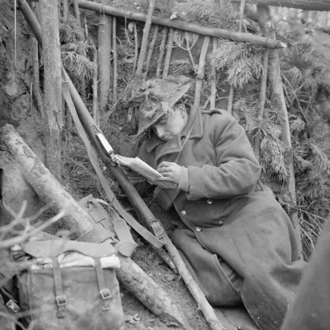 Private Thomas Childs of the 1st Herefordshire Regiment reads a letter from home in his dug-out, March 1945